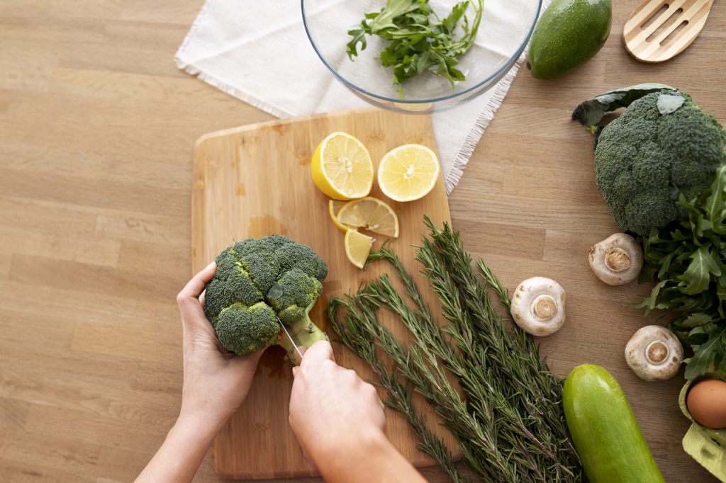 Hands cutting broccoli on a wooden board surrounded by fresh vegetables and herbs, illustrating Health Tips for Vegetarians